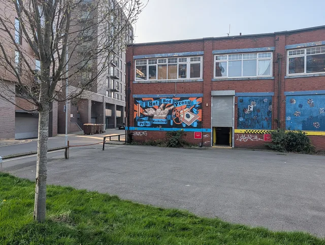 Hot Bed Press is an open-access print workshop in Salford. This picture shows the side of the building facing the street. There is a mural with the name of the press, and a roll-down door that's two-thirds closed. (The main door is down the side street to the left.) In front is a small car park and. How to Build a Print Shop Referral Program