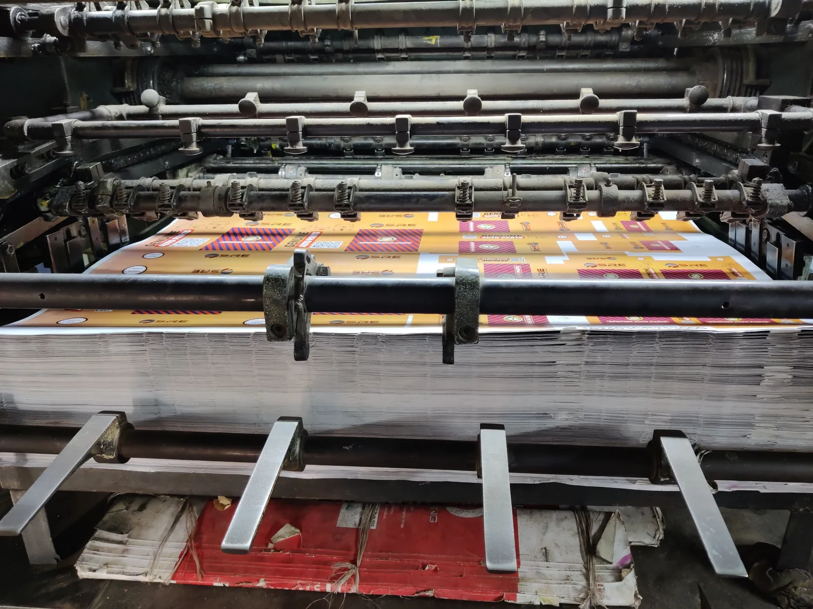 Close-up of an industrial printing machine processing paper sheets in a factory setting. Section 179 and bonus depreciation for American print shop equipment buyers